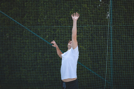 Volleyball player jumping high to serve the ball on a sand court during a sunny day. A dynamic...