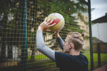 Volleyball player preparing to set the ball near the net on a hard court, focusing on precision and control. Captured from behind, showcasing outdoor volleyball skills.の写真素材