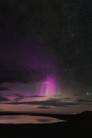 Aurora borealis over Snaefellsnes peninsula, West Iceland, vivid purple and pink hues, starry night sky, serene water reflection, breathtaking natural wonder.の写真素材