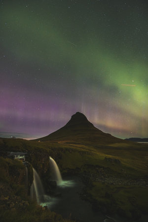 Aurora borealis, northern lights, dances around Kirkjufell mountain on the Snaefellsnes peninsula in West Iceland. Green, pink and red colors.の写真素材