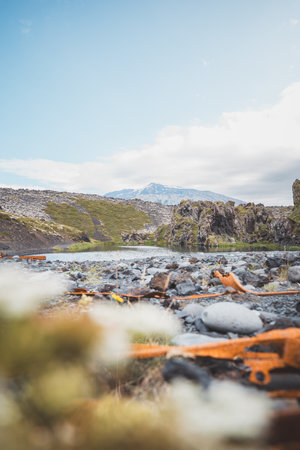 Featuring dramatic volcanic rock formations, a pebble beach, and distant mountains.