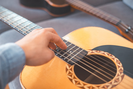 Relaxing on a cozy sofa, a man gently strums his acoustic guitar, lost in music. A peaceful home...