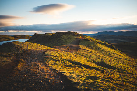 Golden hour over the rolling hills and calm lake near Midfell mountain in Hrunamannahreppur, Iceland. A peaceful sunset moment in the untouched Icelandic countryside.の写真素材