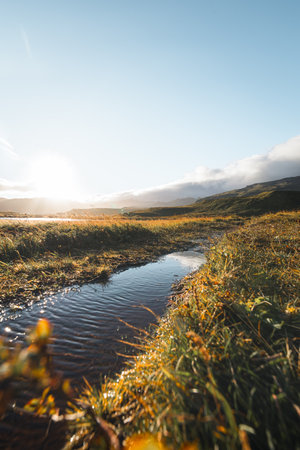 Kirkjufell mountain at sunrise with golden grasslands and soft clouds above, creating a peaceful and iconic Icelandic scene on the Snaefellsnes Peninsula.の写真素材