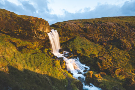 Selvallafoss waterfall on the Snaefellsnes Peninsula in western Iceland, captured as cold, clear water cascades in front of a magical sunset.の写真素材