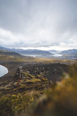 Lone hiker stands on the end of The Horn mountain on Snaefellsnes peninsula in Iceland as golden...