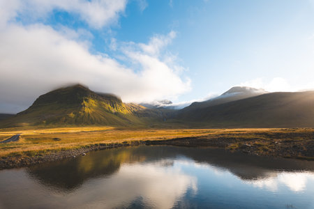 Scenic mountains near Grundarfjordur on Snaefellsnes Peninsula, Iceland, glowing in golden light with dramatic clouds and reflection in lake. Sunset over icelandic and north land.の写真素材