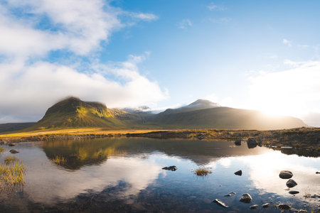 Scenic mountains near Grundarfjordur on Snaefellsnes Peninsula, Iceland, glowing in golden light with dramatic clouds and reflection in lake. Sunset over icelandic and north land.の写真素材