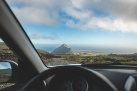 Driving along a rugged gravel road towards a striking mountain peak on Iceland's Snaefellsnes Peninsula. A perfect moment of road trip freedom and adventure.の写真素材