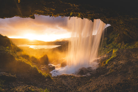 Selvallafoss waterfall on the Snaefellsnes Peninsula in western Iceland, captured from behind as cold, clear water cascades in front of a magical sunset.の写真素材