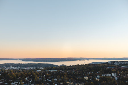 Panoramic sunset paints Oslo fjord and forested hills in soft pastel hues, as the city quietly embraces the golden end of a perfect autumn day.の写真素材