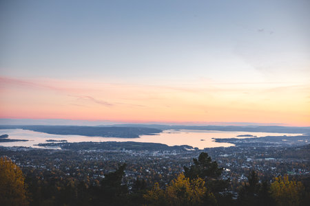 Sunset from Vettakolltoppen paints Oslofjord in soft pastels, offering a serene panorama above the cityâan unforgettable moment of Norwegian autumn tranquility.の写真素材