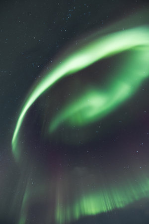 Magical Aurora Borealis in green, red, pink colours above Mortenhals with thousands of stars in the Troms region of Northern Norway. Astronomical phenomena observable from Earth