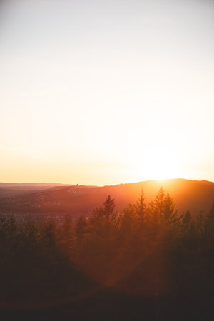 Holmenkollen ski jump rises through golden haze above Oslo pine-covered hills during sunset, glowing in warm Scandinavian spring atmosphere.の写真素材