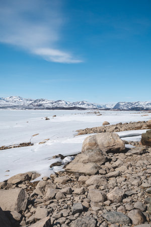 Vast frozen lake with snowy mountains in the distance, Hardangervidda plateau, Norway. Pure Arctic calm and endless northern wilderness.の写真素材