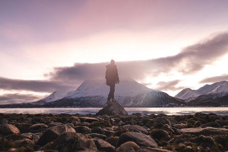 Silhouette of a traveler on a rocky Arctic coast in the Troms