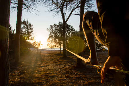 Walking on slackline in front of the sea in backlightの写真素材