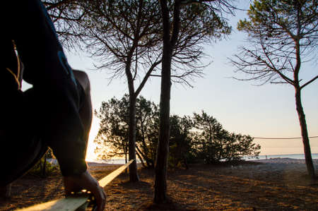 Walking on slackline in front of the sea in backlight