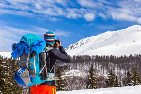 bla bla Young caucasian man photographer talking pictures while backcountry skiing on a beautiful sunny day with fresh snowの写真素材