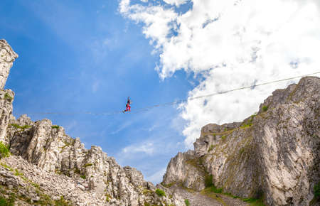 Young slackliner man balancing on a slackline betweend two rocks. Highline with a beautiful natural landscape behindの写真素材