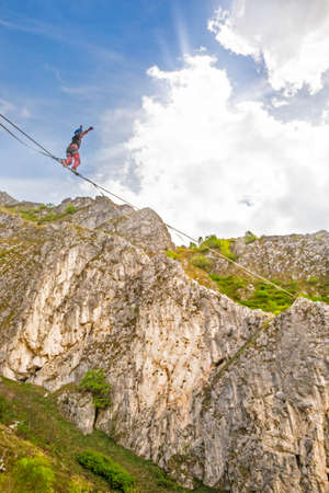 Young slackliner man balancing on a slackline betweend two rocks. Highline with a beautiful natural...