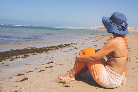 Woman in bikini is on vacation sitting on the beach in summer.の写真素材