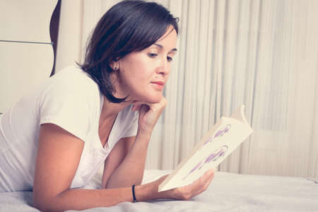 girl on the bed reading a bookの写真素材