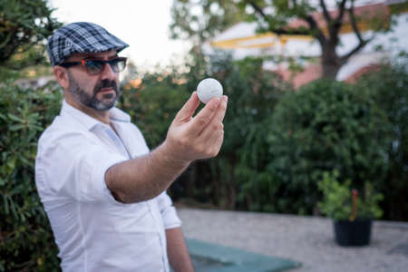 man showing golf ball in his hands