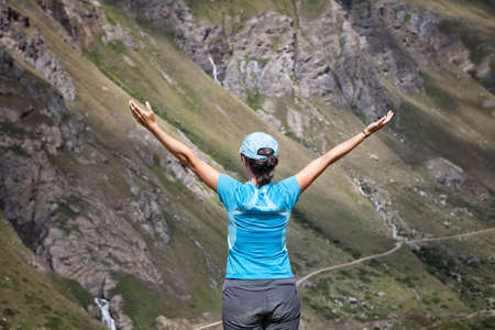 woman with backs open arms in a mountainous landscapeの写真素材