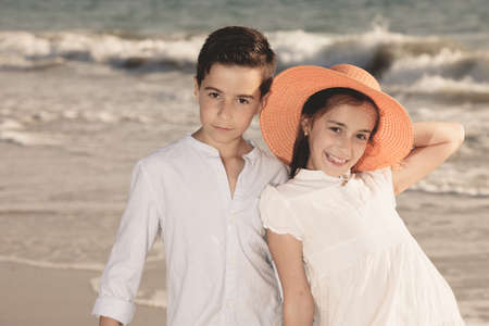 boy and girl on the beach, she with an orange hatの写真素材