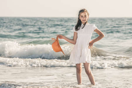 girl on the seashore wearing an orange hat and a white dressの写真素材