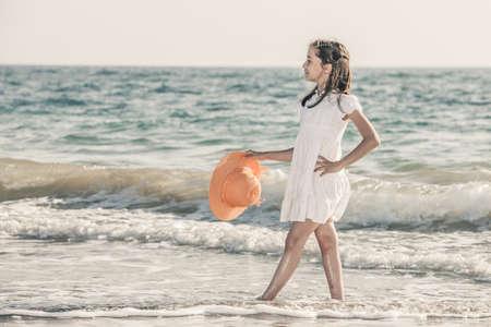 girl on the seashore wearing an orange hat and a white dressの写真素材