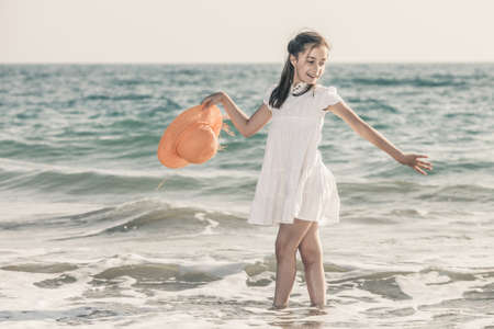girl on the seashore wearing an orange hat and a white dressの写真素材