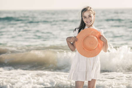 girl on the seashore wearing an orange hat and a white dressの写真素材
