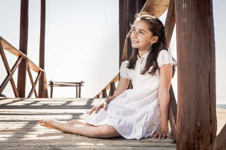 girl sitting on wooden floor on the beachの写真素材