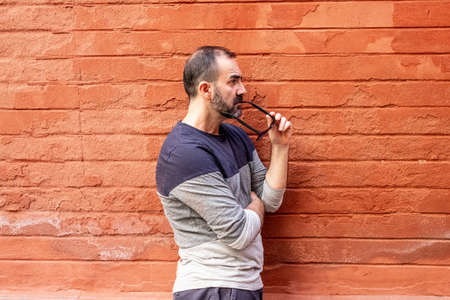 man standing with some glasses in his mouth in front of a red wallの写真素材
