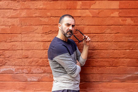 man standing with some glasses in his mouth in front of a red wallの写真素材