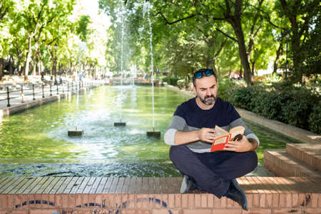 man sitting in a park reading a bookの写真素材