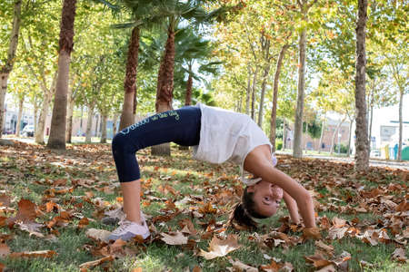 little girl making the bridge in a park
