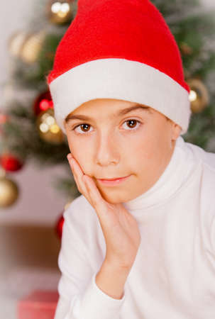 boy with hand on face and santa hat in studioの写真素材