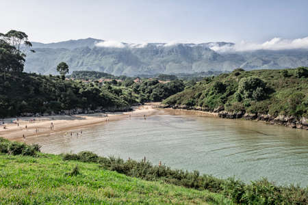 people bathing in a beach surrounded by mountains in an Asturian landscapeのeditorial素材
