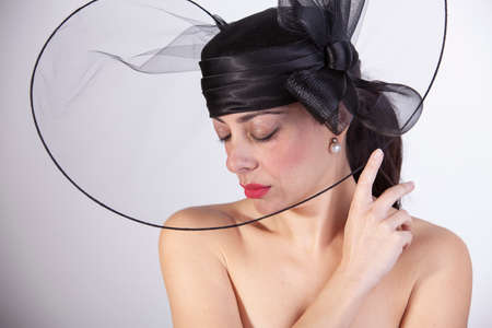 Beautiful woman with red lips, and closed eyes with black hat and black suit. retro fashionの写真素材