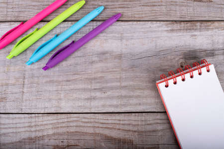 notepad and set of colored pens on wooden background