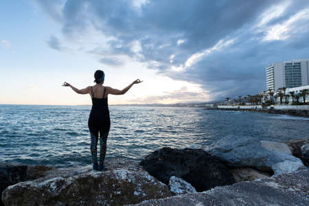 Woman practicing yoga on the beach on a cloudy dayの写真素材