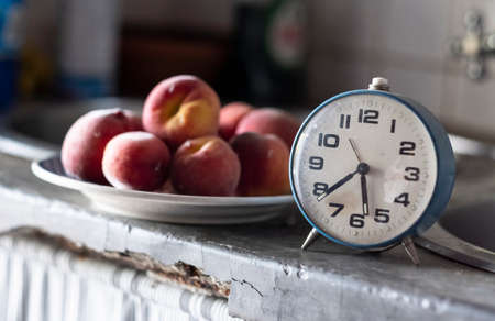 old blue clock in front of a plate of plumsの写真素材
