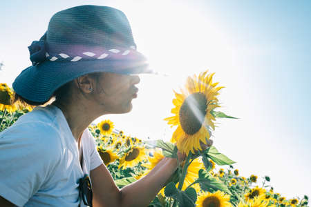 woman with hat kissing a sunflower plant