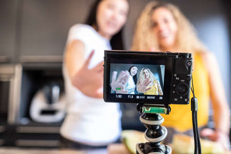 chinese girl and white girl shooting a video in the kitchen for blogの写真素材