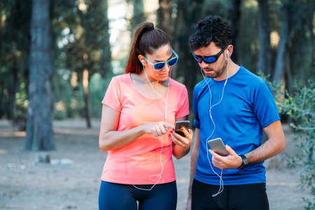 Caucasian couple watching mobile application and exercising in a park. Healthy living conceptの写真素材