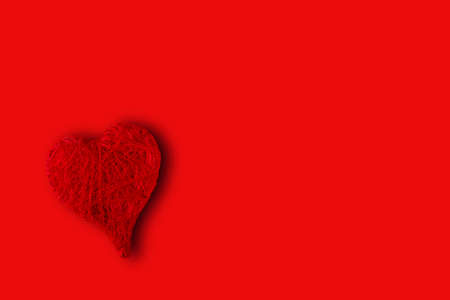 red heart in the lower left corner on a red background. Concept of St. Valentine's Dayの写真素材