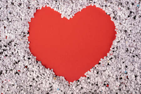 pieces of small white papers forming a heart on a red background. Concept of St. Valentine's Dayの写真素材
